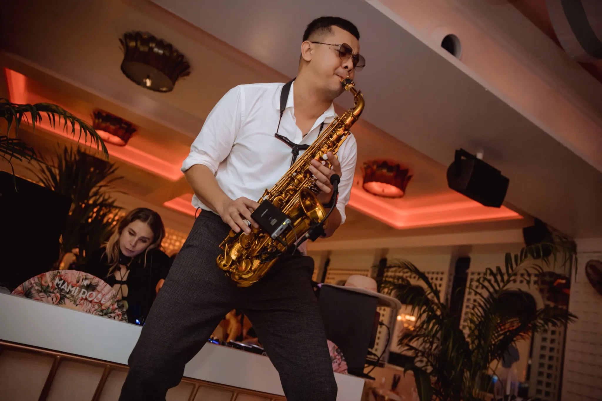 Close-up of a saxophonist performing at Mami Rose, a stylish restaurant on the 5th floor of EMSPHERE Mall in Bangkok, with a DJ in the background.