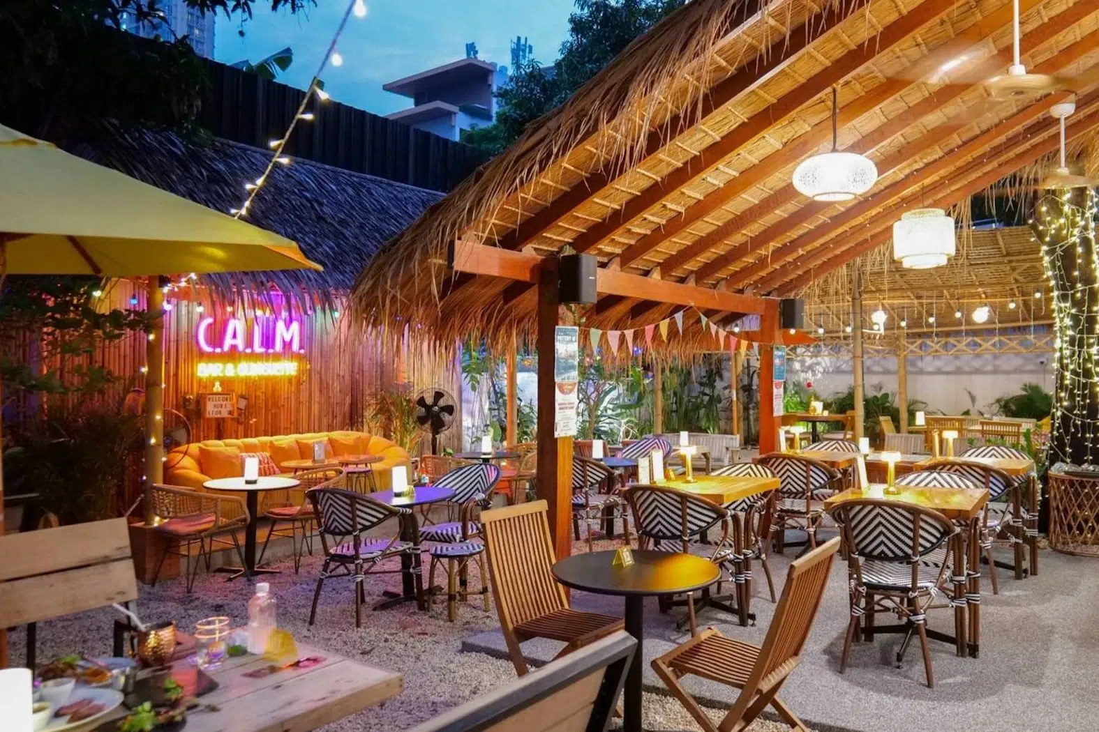 The restaurant is decorated in an outdoor beachside style, featuring yellow sofas amidst the evening atmosphere.