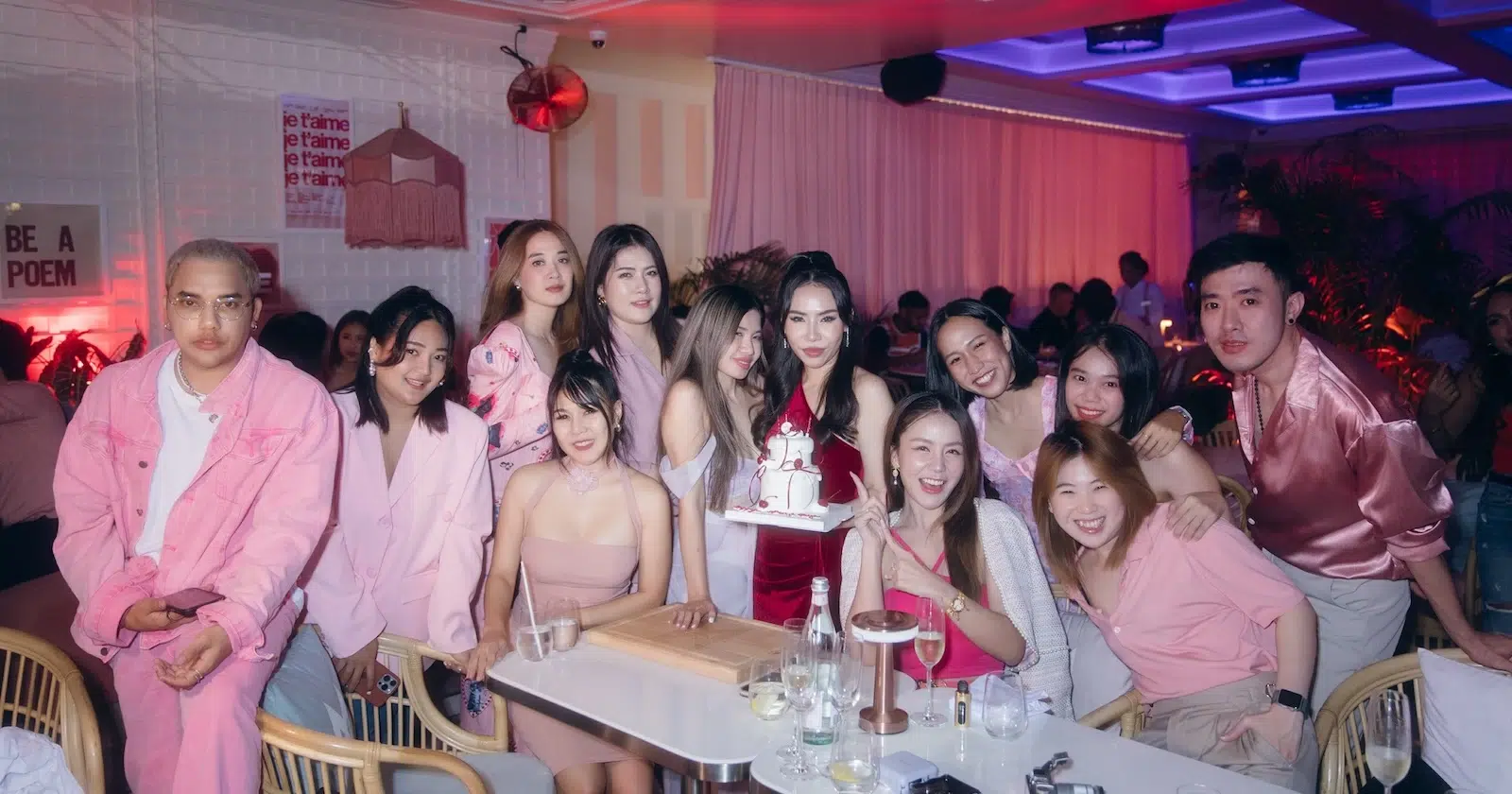 A group of friends celebrating a birthday with a pink-themed dress code.