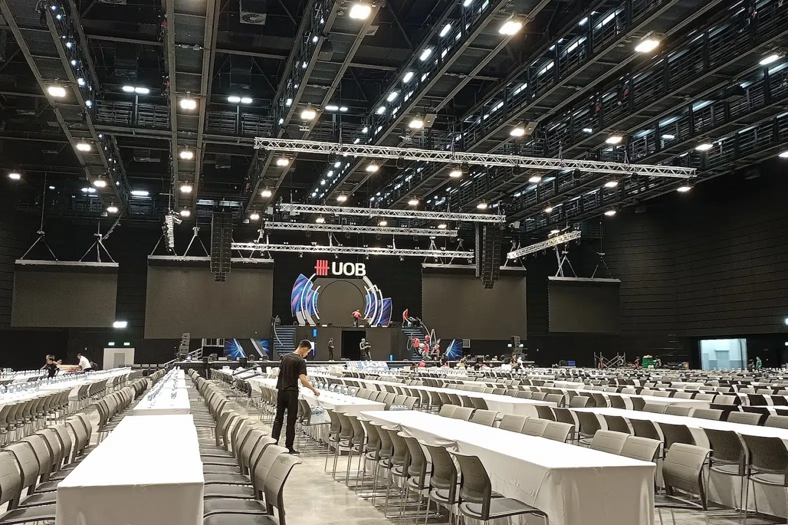 You can see the main hall of UOB Live at EmSphere mall in Bangkok. Here the UOB Live hosts a professionnal seminar. Staff are preparing the tables for the event.