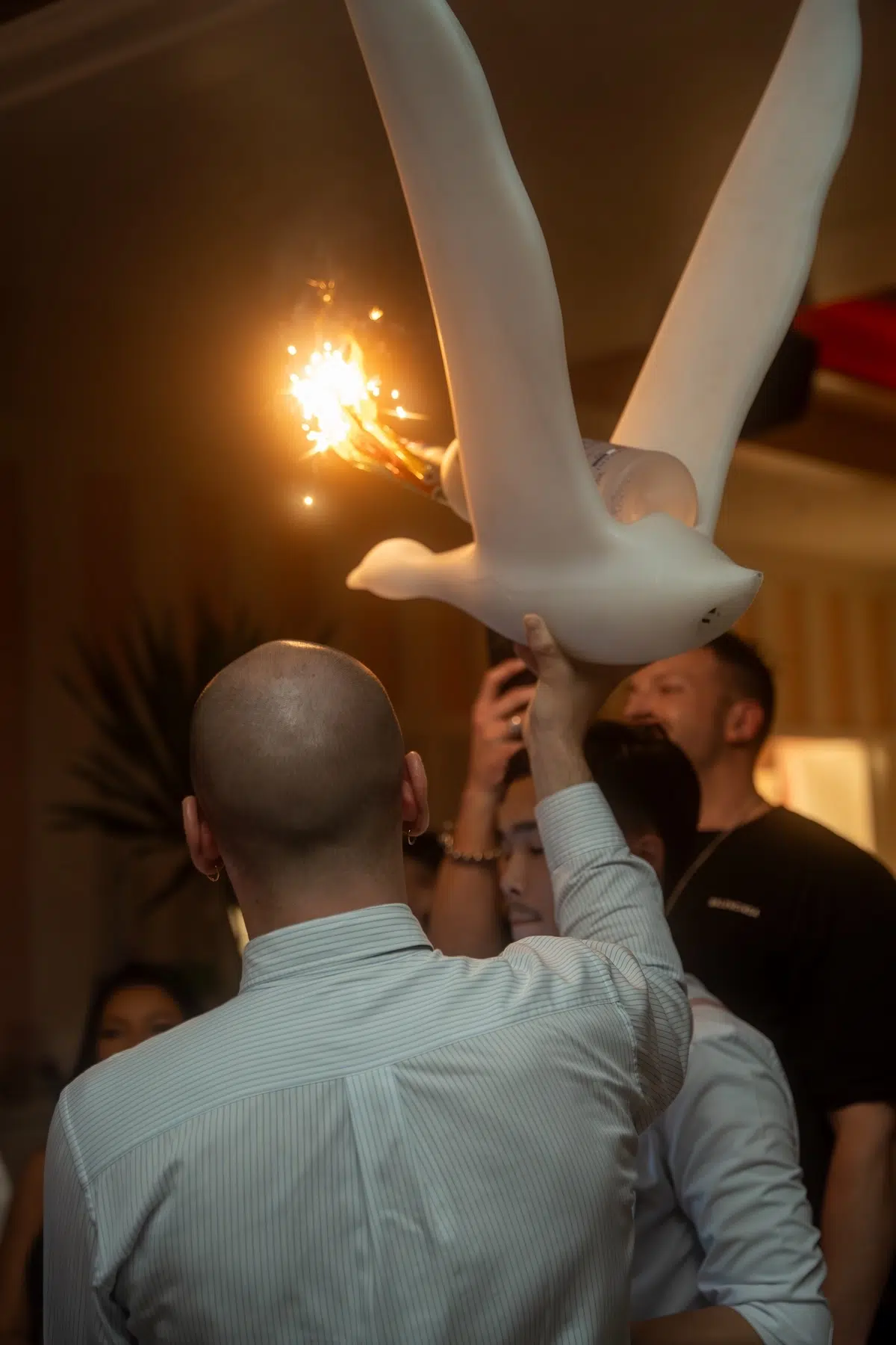 waiter holding a bottle of Grey Goose with sparklers sitting on a white goose sculpture at Mami Rose restaurant in Bangkok